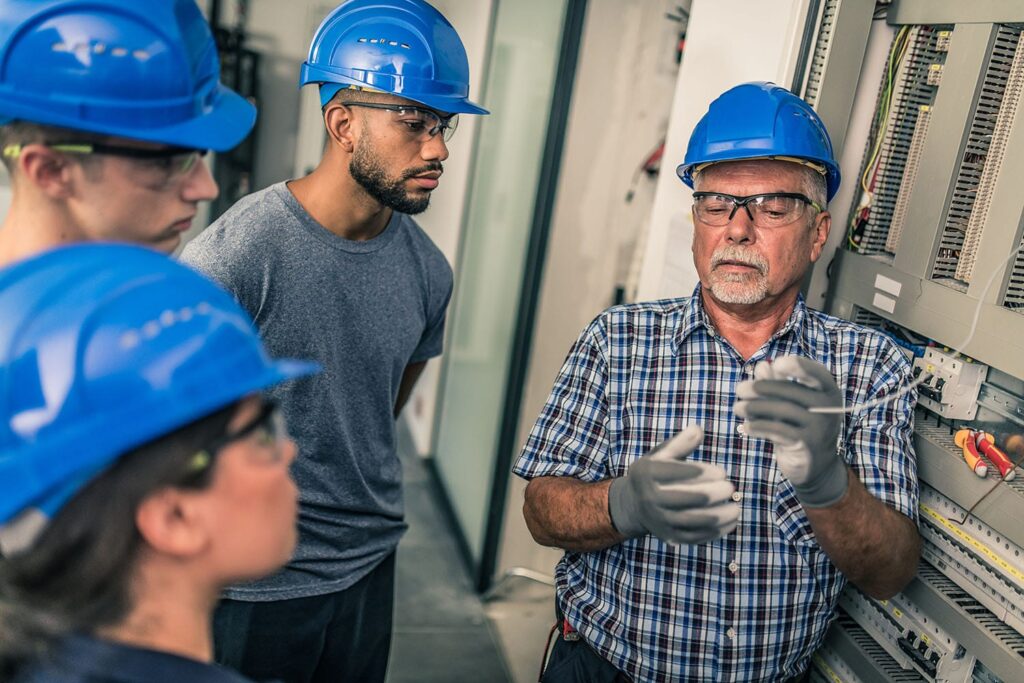 Three apprentices learning about switchboards